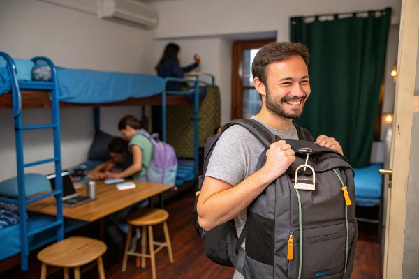 Happy traveler with a secure backpack in a shared hostel room, ideal for group accommodations