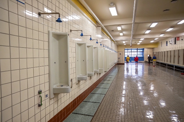 Locker room with several shower stalls and floor mats.