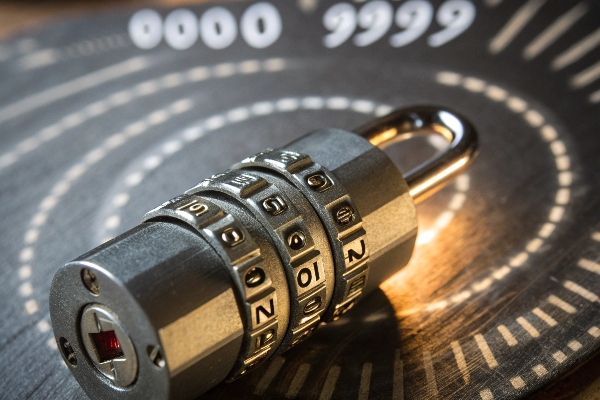 Combination lock with numeric dials, placed on a background displaying a numeric range from 0000 to 9999.