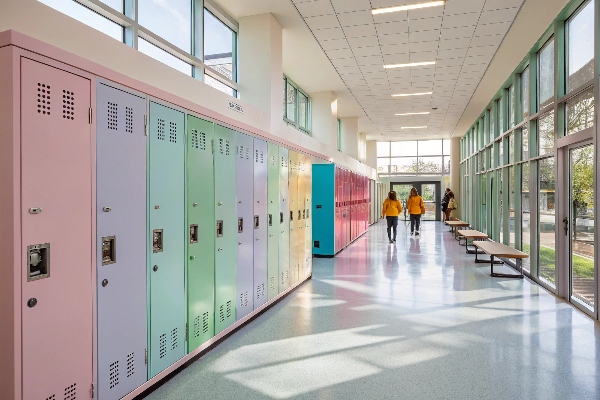 Pastel-colored lockers in a sunlit school hallway with large windows.