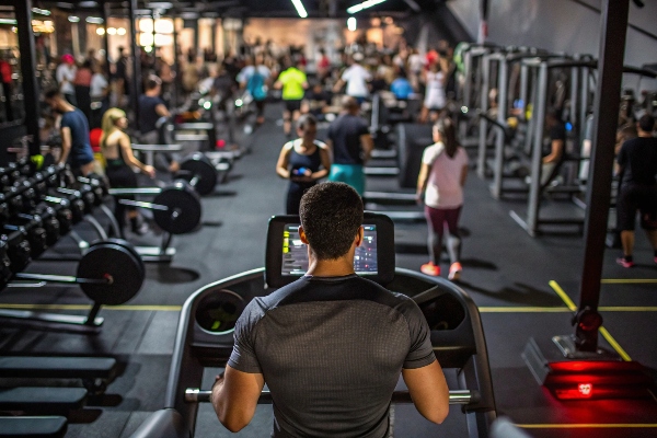 Busy gym with people exercising on treadmills and weight machines.