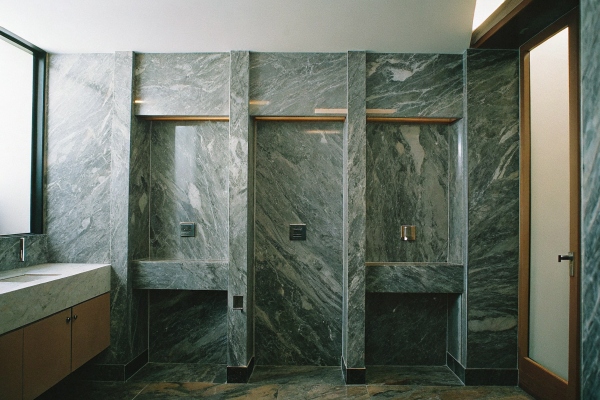 Modern restroom with marble partitions and integrated shower spaces.