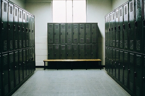 Steel lockers in a clean changing room with a wooden bench.