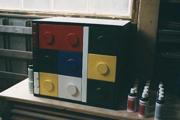 Compact colorful locker with round handles on a wooden workspace.