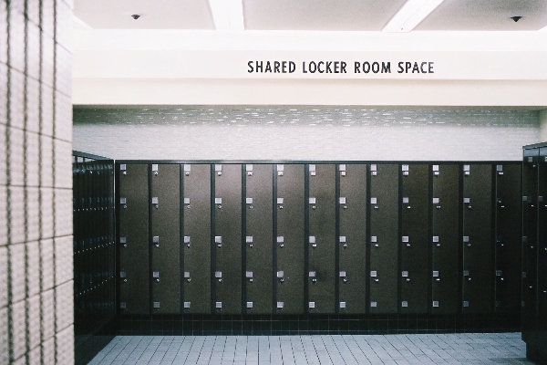 Shared locker room space with dark steel lockers and tiled walls.