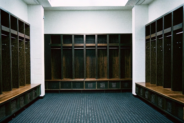 Elegant gym locker room with wooden lockers, benches, and indoor plants.