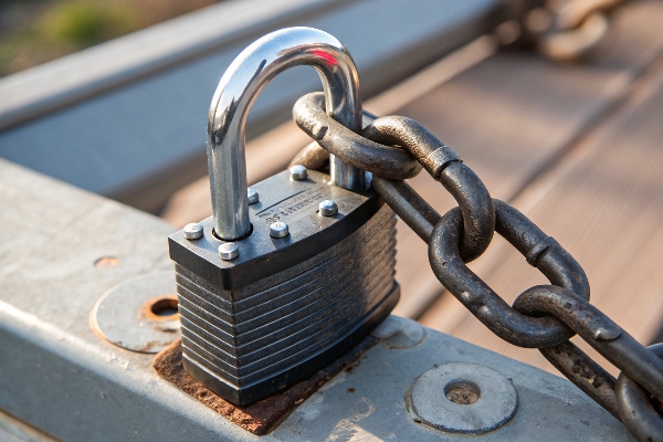 Close-up of a padlock securing a chain to a metal gate