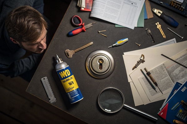 Locksmith working with tools and lock lubricant on a workbench