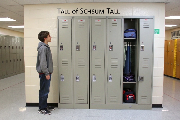 Student standing next to tall lockers with clothing inside